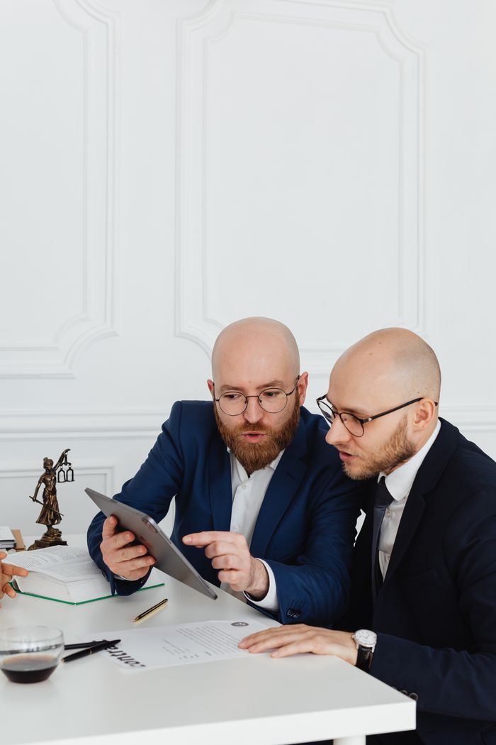 Two professionals discussing with a digital tablet during a business meeting in an office setting.